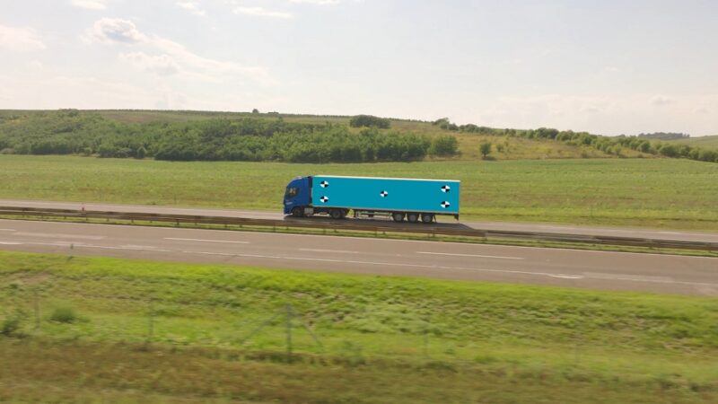 FTL shipping truck driving along a highway through green countryside, showcasing full truckload freight in motion