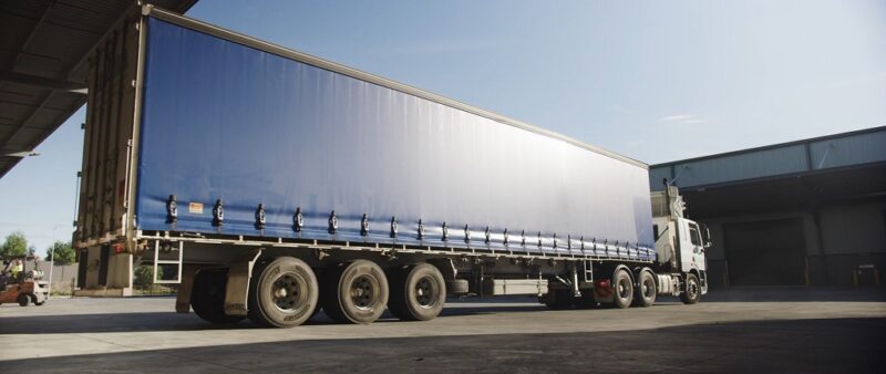 A large blue FTL shipping truck parked at a warehouse dock, ready for a full truckload delivery