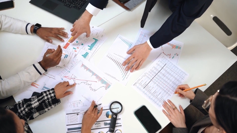 Team reviewing charts and financial reports during break-even analysis for profit, cost, and revenue strategy