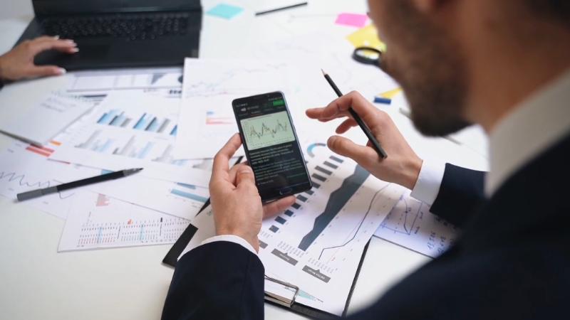 Business professional reviewing charts on a phone during marginal analysis of production decisions