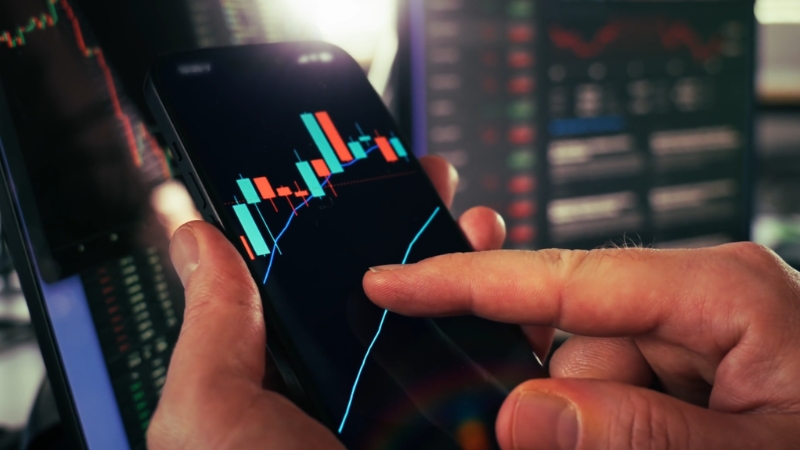 Person analyzing stock market charts on a phone while reviewing industry margin trends