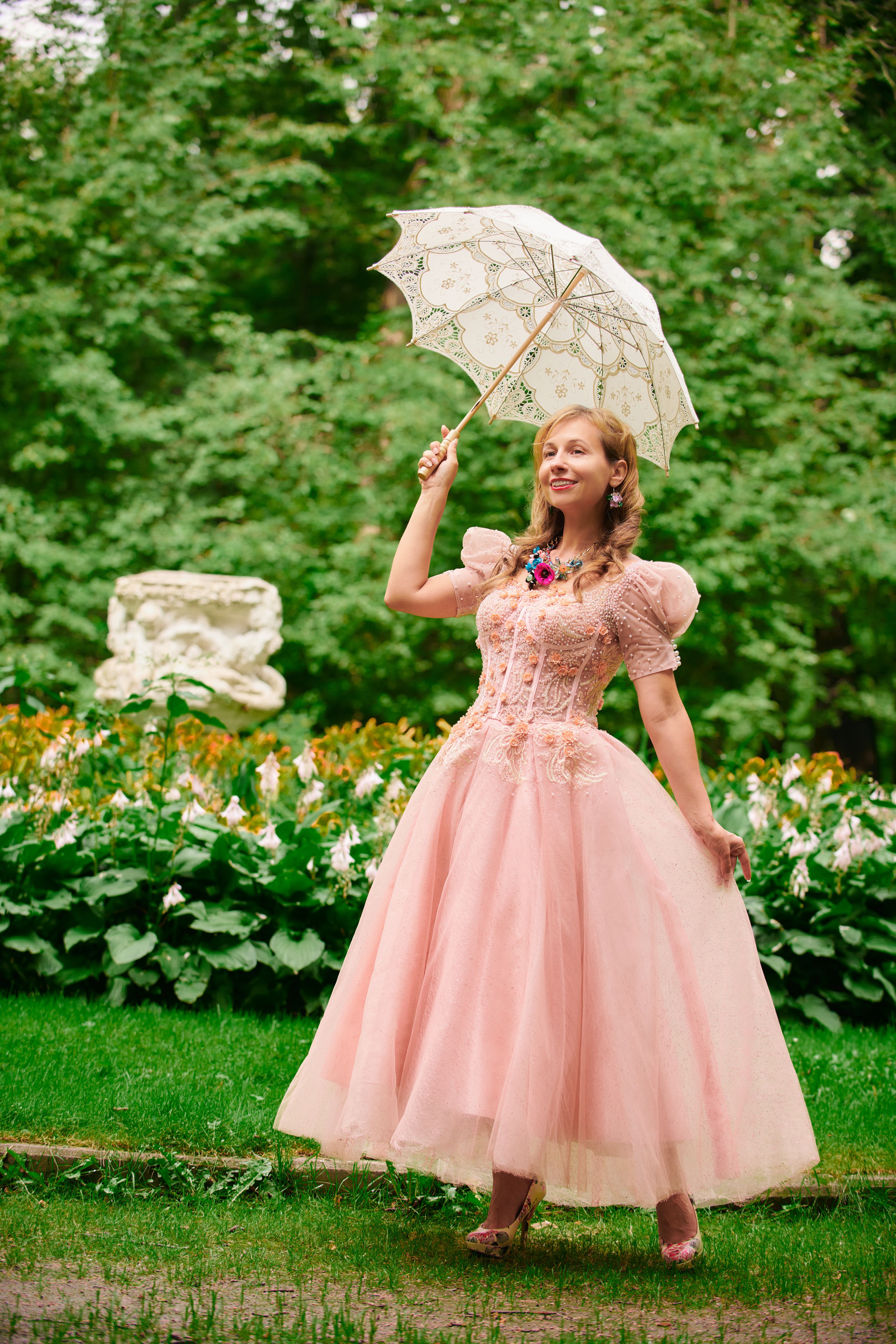 Woman in Victorian pink gown holding a parasol in a garden, reminiscent of 19th-century courtesan fashion